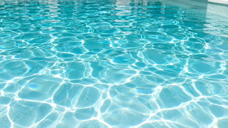 Crystal clear pool water with sunlight patterns on a white floor