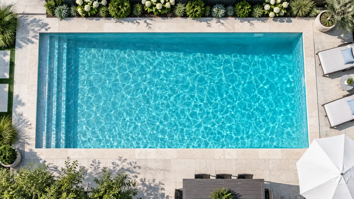 Top-down aerial view of a rectangular lap-style inground pool with straight edges and light stone coping